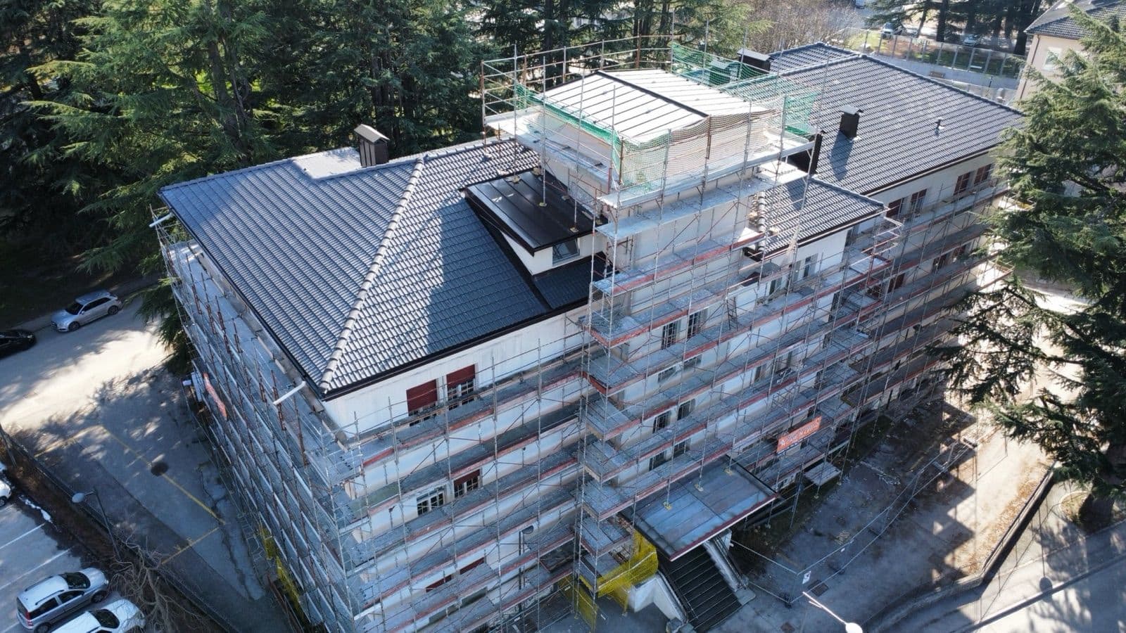 Edificio in costruzione con ponteggi perimetrali e copertura in legno finita con tegole coppo di Francia
